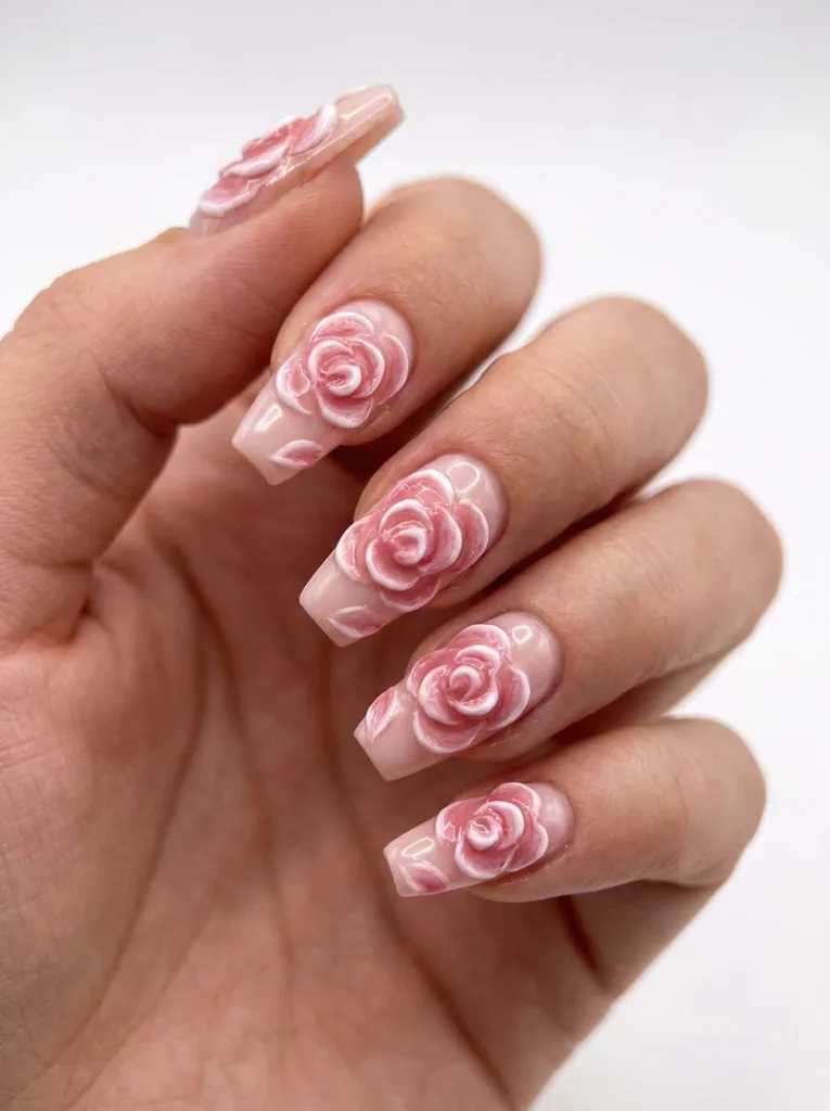 Coffin-shaped blush pink nails with fully sculpted 3D gel rose petals raised above the nail surface in rose pink and white