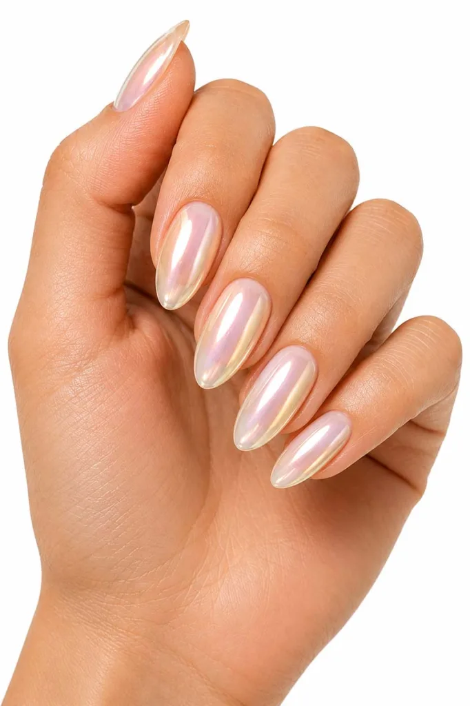Close-up portrait of a hand with medium almond nails in a chrome-pearl glazed finish reflecting soft white, pale pink, and gold tones against a pure white background under bright studio lighting.