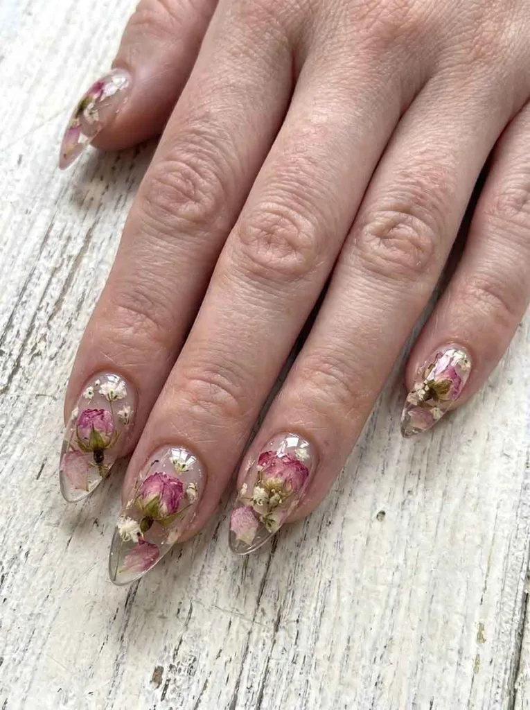 Stiletto-shaped clear hard gel nails with real dried pink rosebuds white baby's breath and pressed petals encapsulated inside