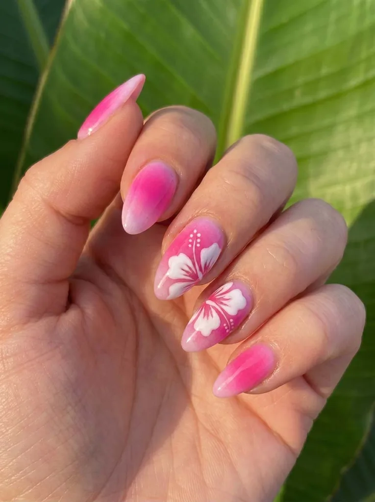 Almond-shaped hot pink aura nails with a bold white hibiscus flower and fine stamen detail painted on the accent nails