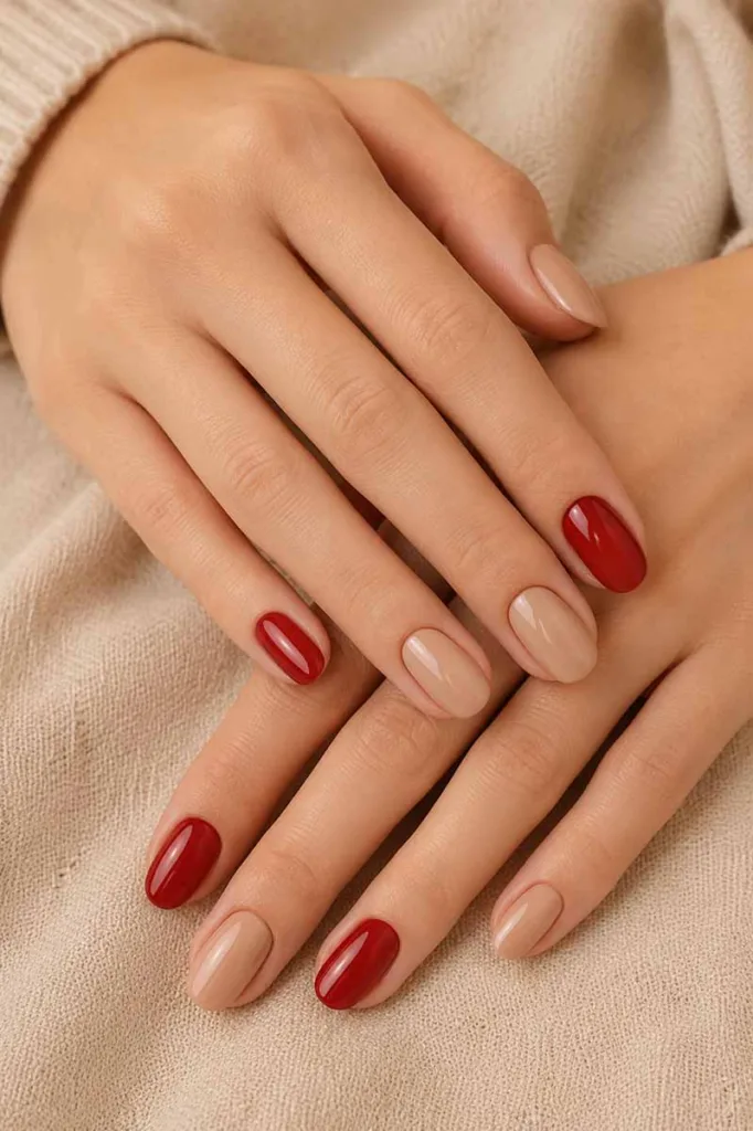 Detailed close-up of glossy scarlet red almond nails featuring delicate white pearl bead accents along the cuticle resting on soft cream satin fabric with warm elegant lighting.