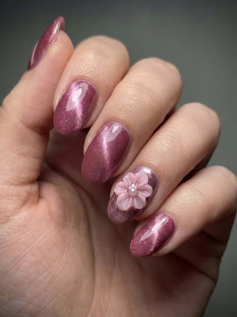 Oval deep pink cat-eye magnetic gel nails with a shifting light stripe and a sculpted 3D pink flower on the accent nail