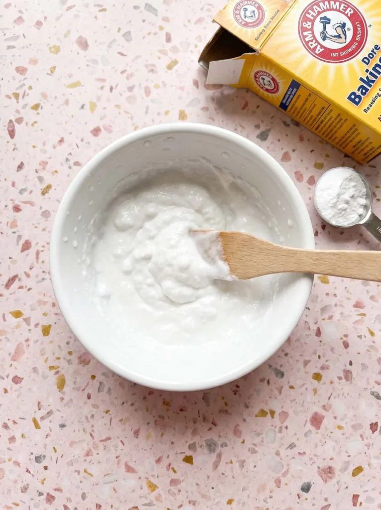 Small white ceramic bowl with baking soda and water mixed into a thick paste for a natural scalp exfoliant treatment