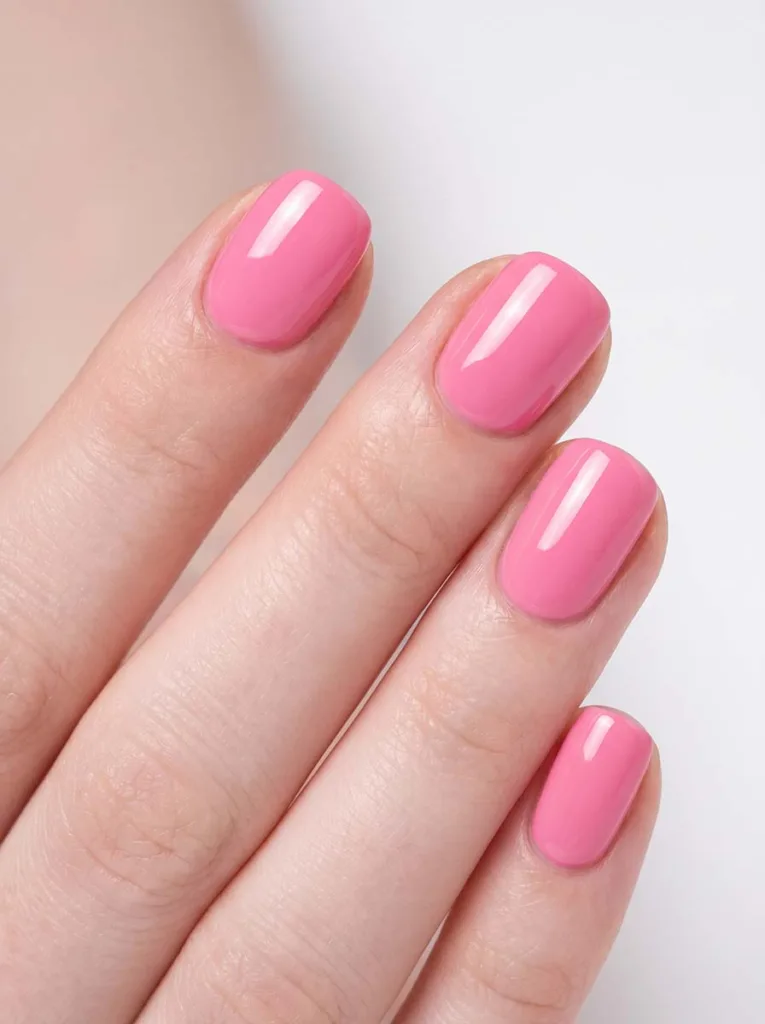 Candy pink high-gloss short round nails on fair skin — macro shot showing mirror-bright specular highlight on rounded tips