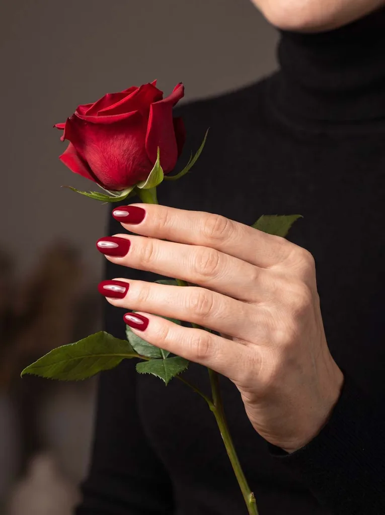cherry red short almond nails glossy creme finish on fair skin hand holding red rose stem