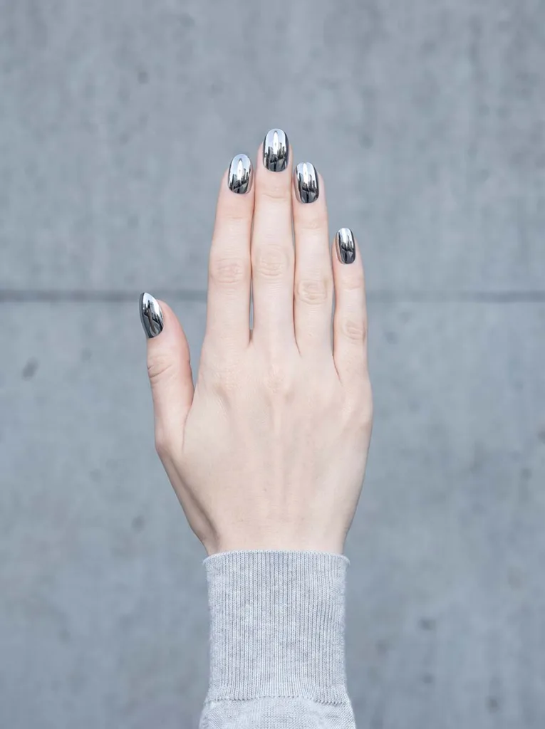 silver chrome mirror finish almond nails with full reflective surface on fair skin studio shot