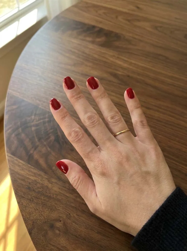 Classic red nail polish on short squoval nails with high-gloss finish on fair skin