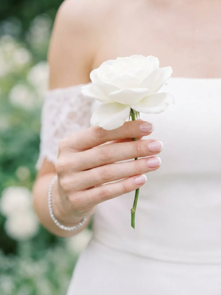 Short nails with classic French tip manicure held elegantly for a formal wedding or event occasion