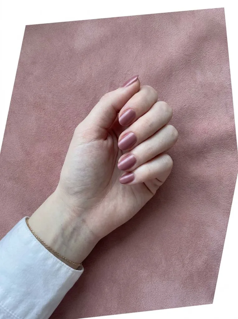 Dusty mauve satin finish nail polish on short oval nails as a modern nude alternative on fair skin