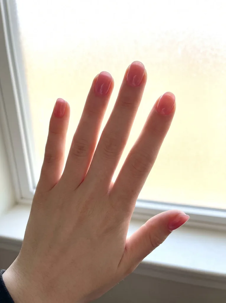 Jelly pink short round nails on fair porcelain skin backlit by window — luminous translucent glow effect