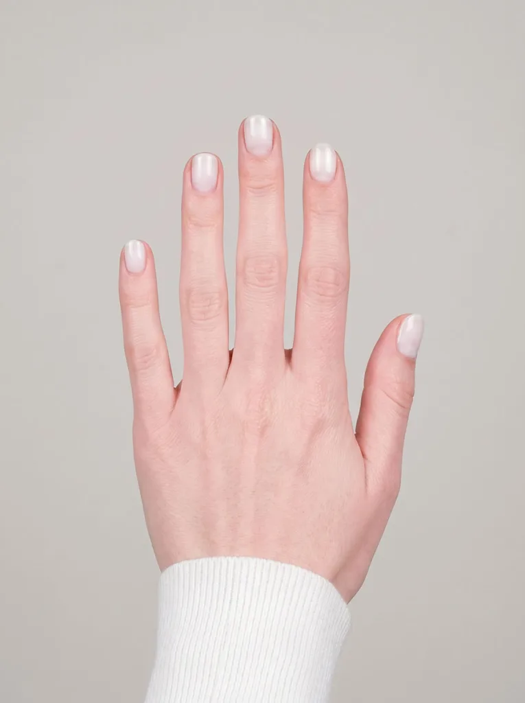 Milky white sheer short round nails on fair skin — straight-on professional lookbook shot on grey background