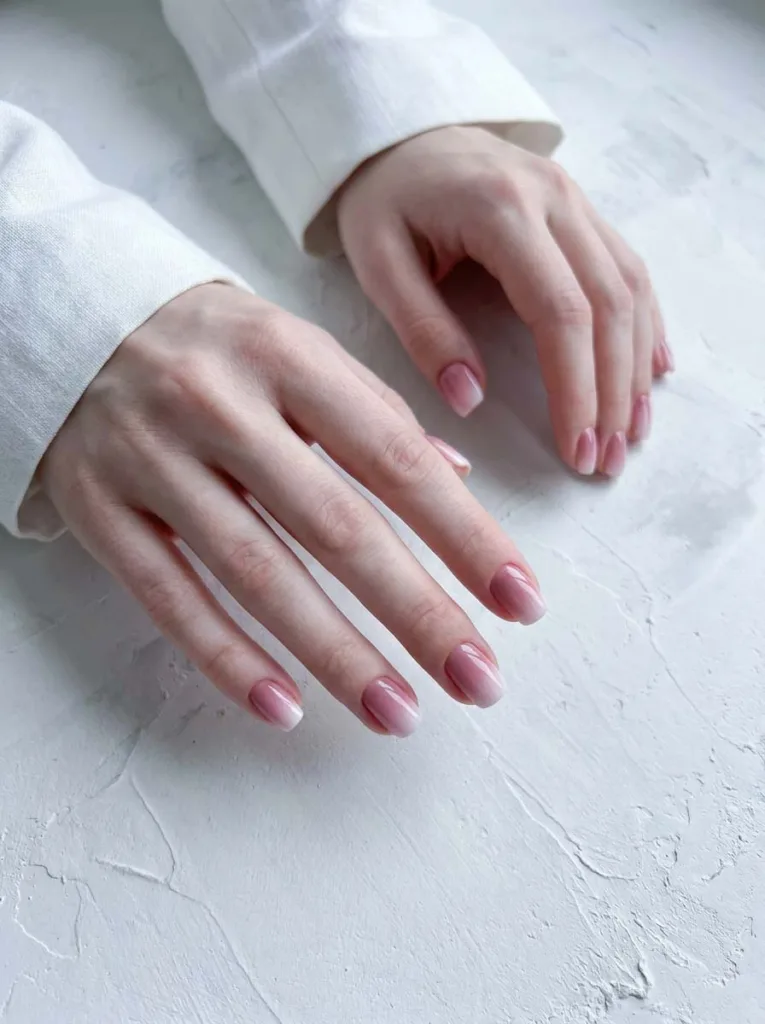 Soft blush pink to white ombre gradient nail design on short squoval nails with glossy gel finish
