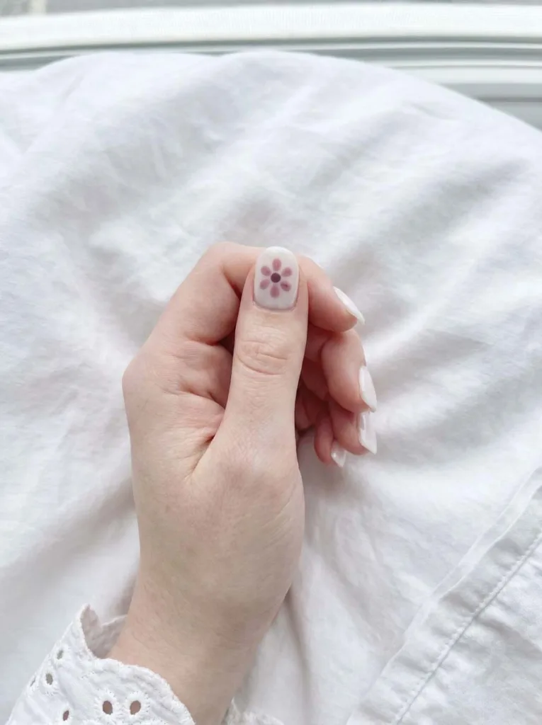 Single small 3D flower accent nail art on nude short nails with one floral design nail and plain nails