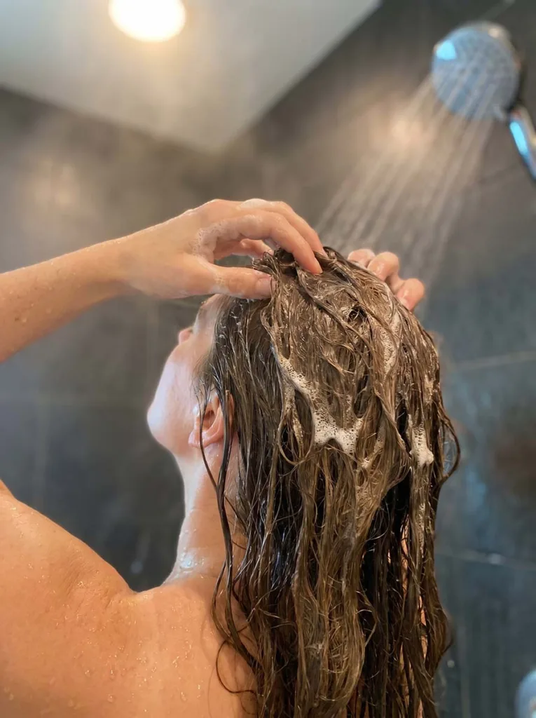 woman massaging sulfate-free shampoo into wet scalp in the shower