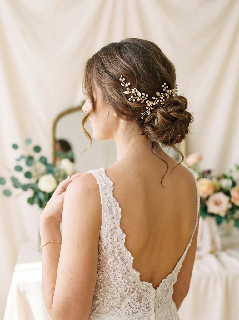 Textured low bun bridal hairstyle with loose tendrils for wedding day 2026