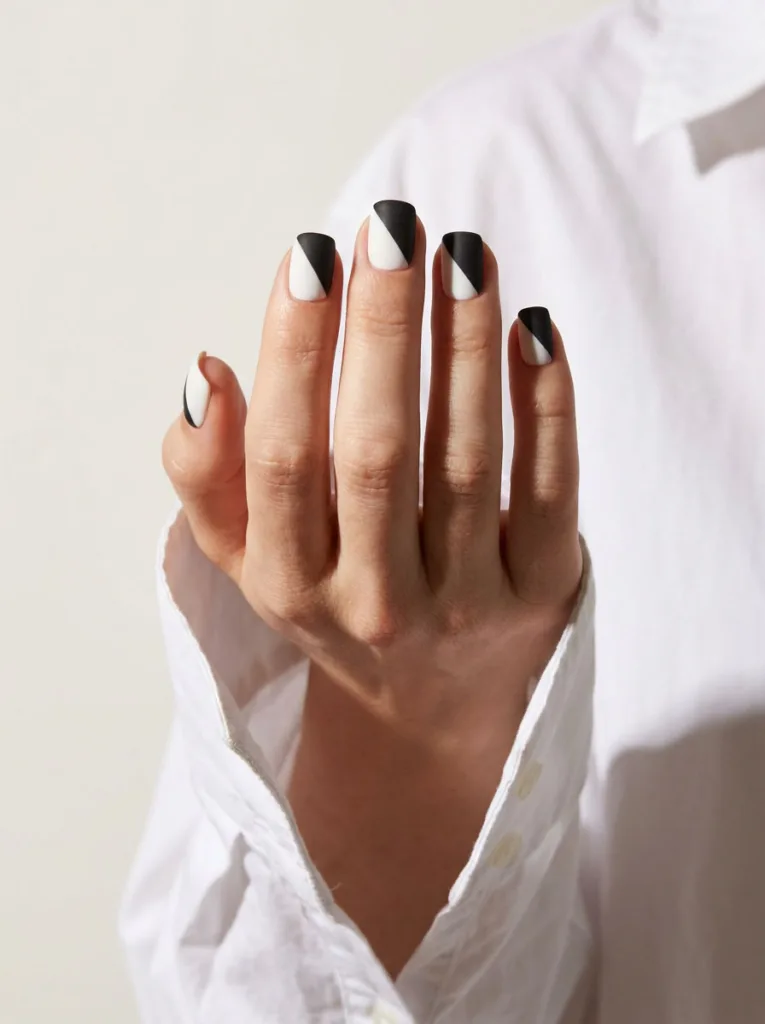Two-tone color block nail art on short nails with diagonal black and white split design