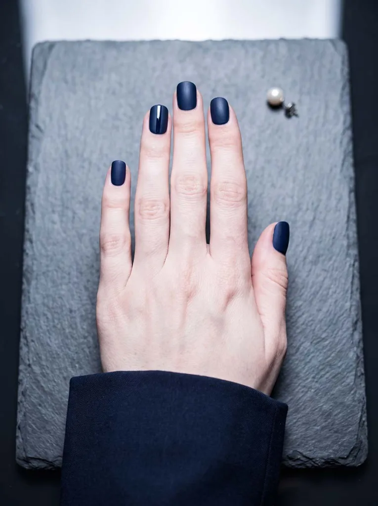 deep navy velvet matte almond nails with single glossy accent line detail on fair skin