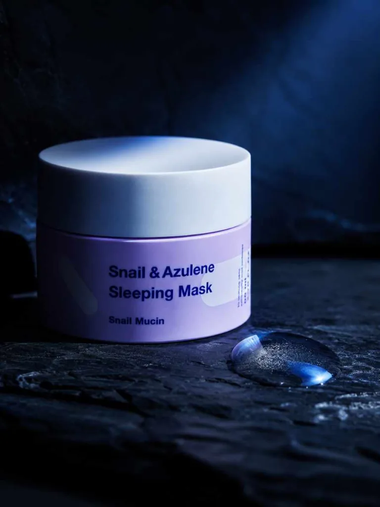 TIA'M Snail and Azulene Sleeping Mask jar on dark slate with a gel droplet