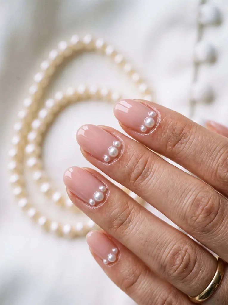 close-up of 3D pearl accent wedding nails beside pearl jewelry