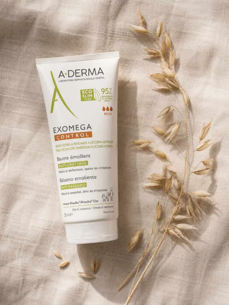 A-Derma Exomega Control tube with its green oat-leaf logo resting on natural linen with dried oat stalks
