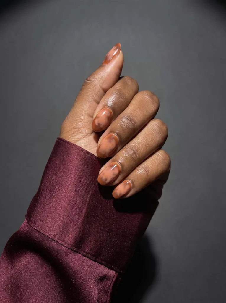 Aura nail art in burnt orange and peach on deep skin tone