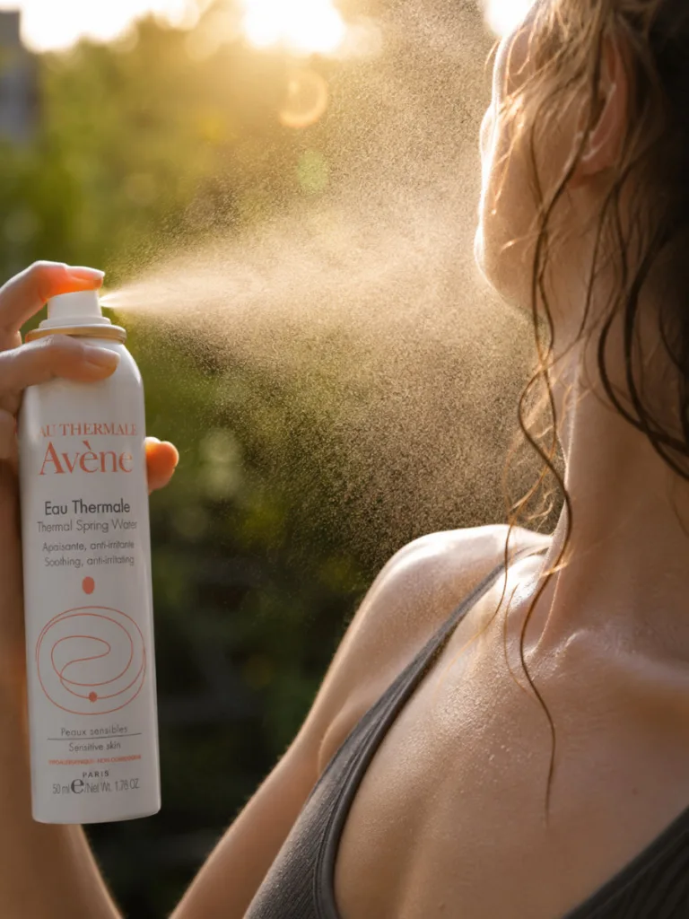 Avène thermal spring water spray captured mid-mist over a bare shoulder after a workout