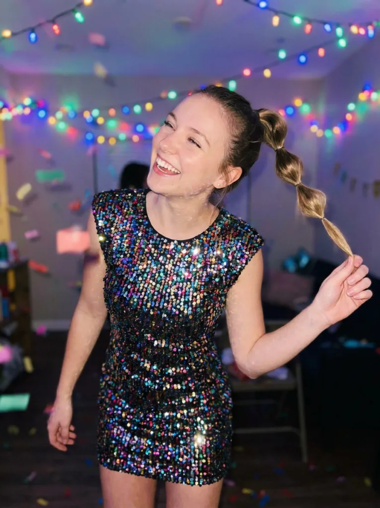 Woman with a bubble ponytail updo dancing at a festive holiday party.