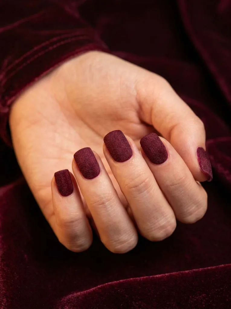 Burgundy velvet matte winter nails on dark velvet background