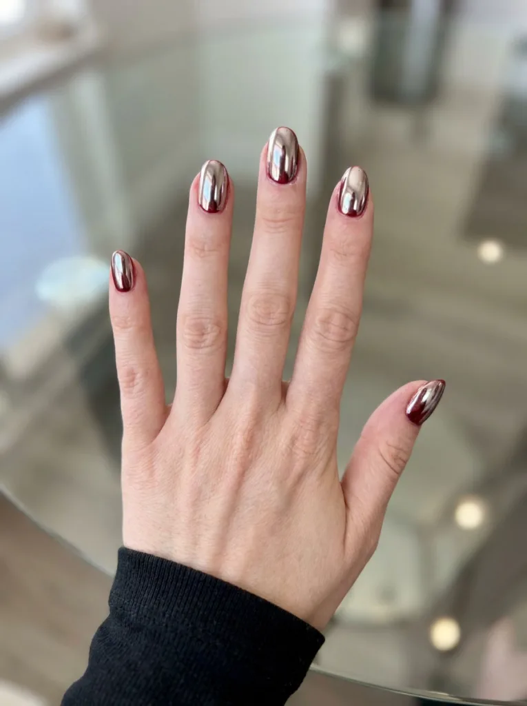 Chrome red christmas nails with a mirror-like finish on a glass tabletop