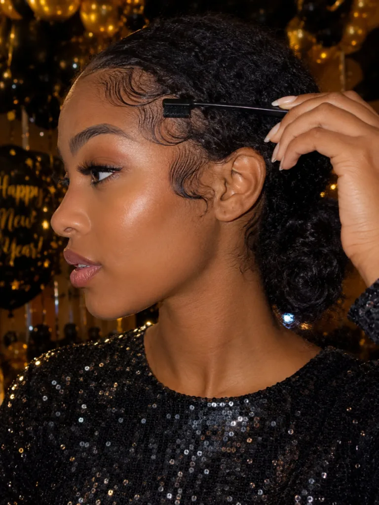 Close-up of a curly low bun with laid baby hairs for a New Year's Eve party.