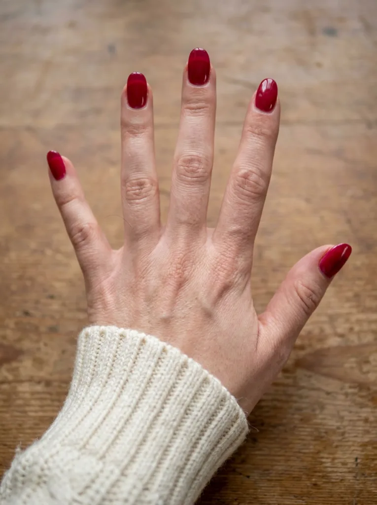 Overhead close-up of glossy cranberry glass-effect Thanksgiving nails
