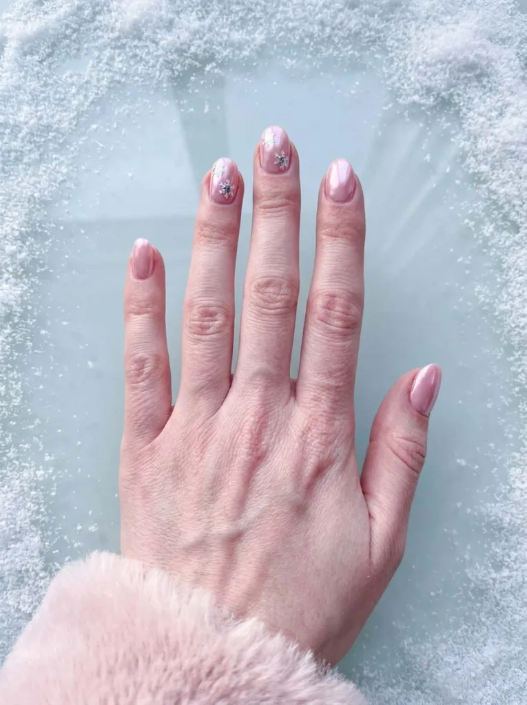 Frosted pink chrome winter nails with snowflake decal accents