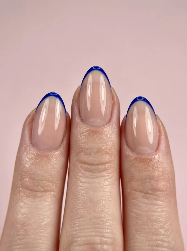 Macro close-up of fingertips with micro French royal blue nail tips