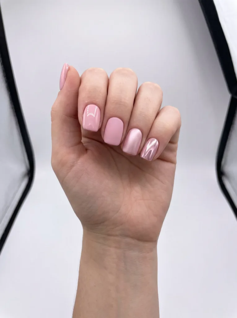 Four fingers showing glossy matte satin and chrome nail polish finish types on the same pale pink shade for comparison