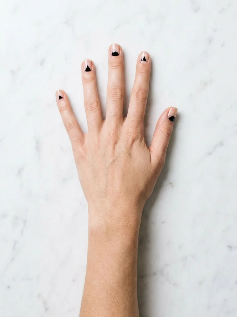 Negative space black and white Christmas nail design on a marble surface