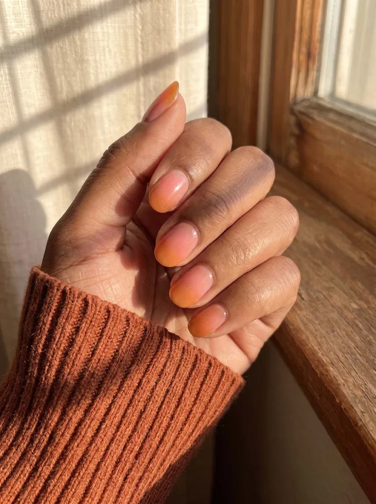 Peachy gradient nails fading from orange to pink on medium skin