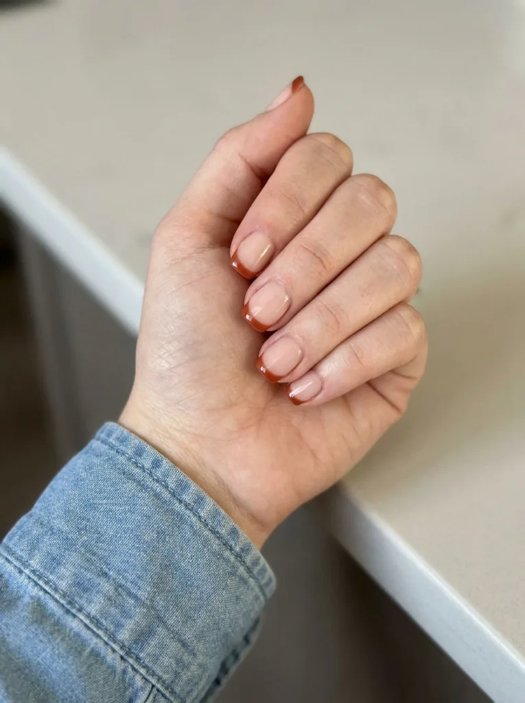 Close-up of short square burnt sienna French tip nails