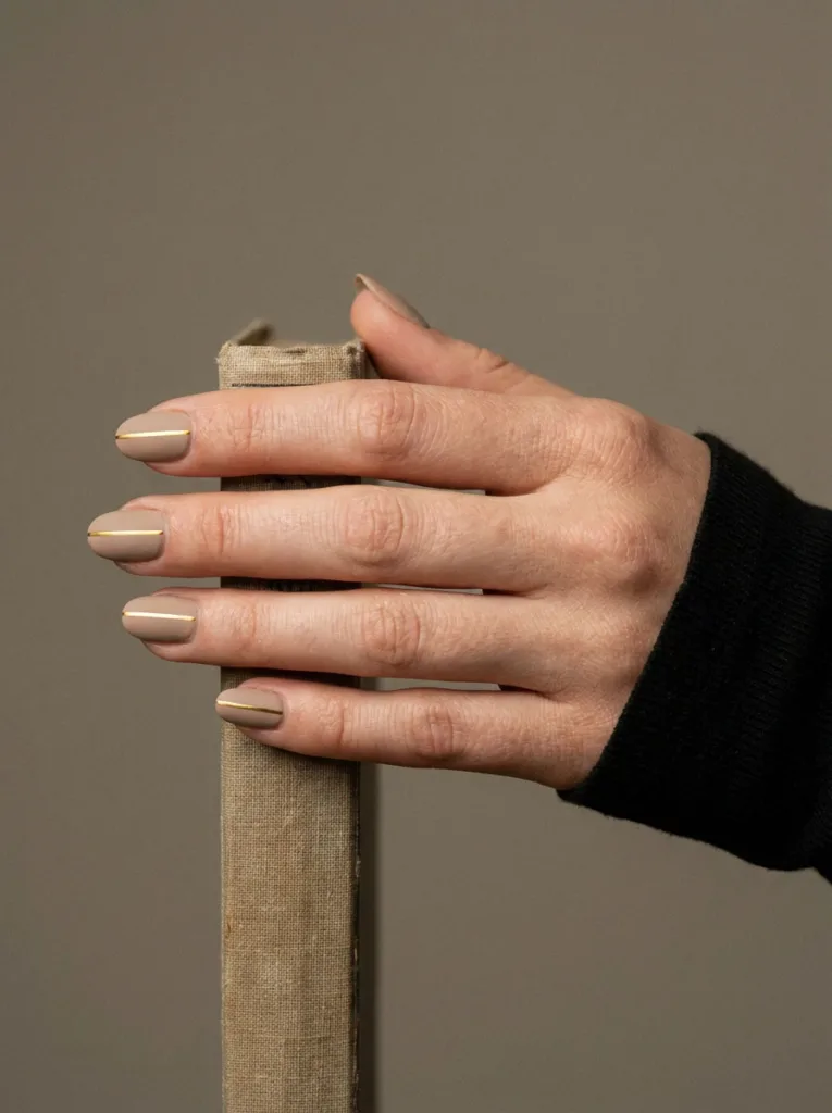 Close-up of simple gold line nail art on a matte base