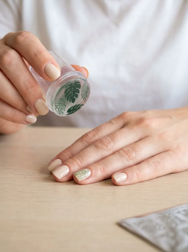 Close-up of a leaf pattern being stamped onto a fingernail