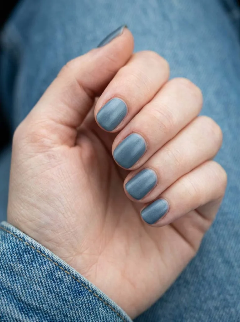 Steel gray-blue matte winter nails on denim background