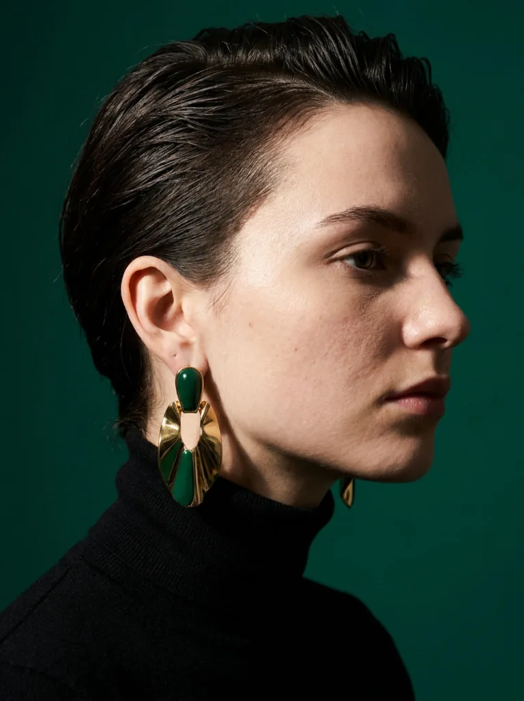 Close-up profile of a textured pixie sweep hairstyle against an emerald backdrop.