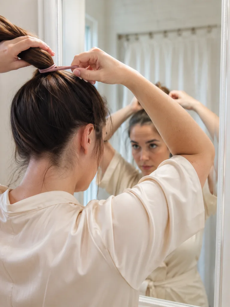 Woman tying a tight high ponytail showing a hair habit that damages your hair