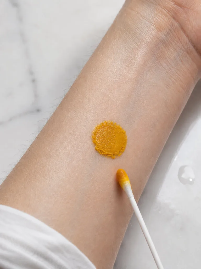 Close-up of a turmeric paste patch test on the inner forearm before full facial application
