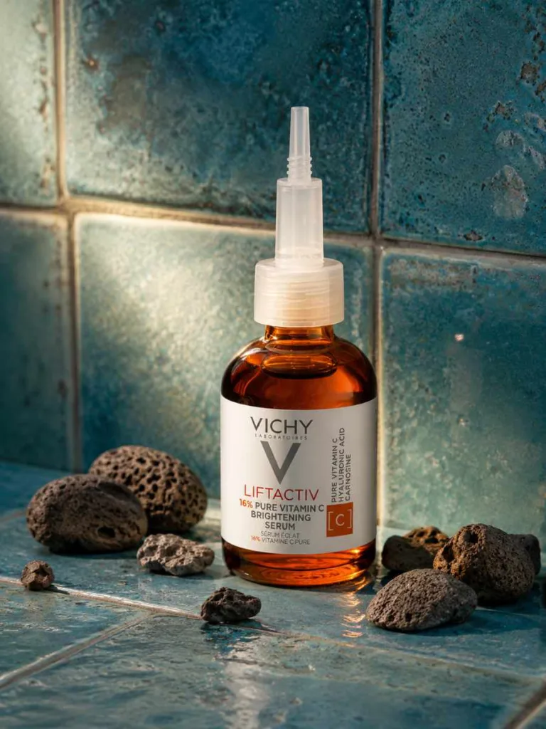 Vichy Liftactiv Vitamin C Brightening Corrector bottle on teal tile with stones
