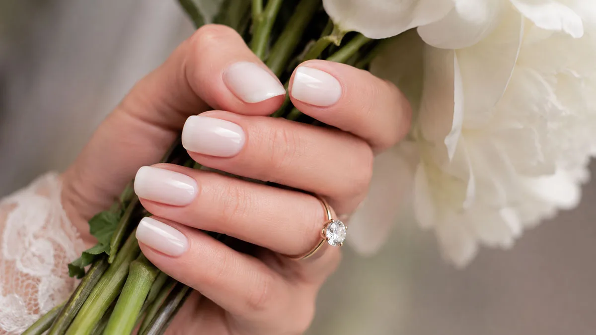 Close-up of a milky white wedding manicure and engagement ring