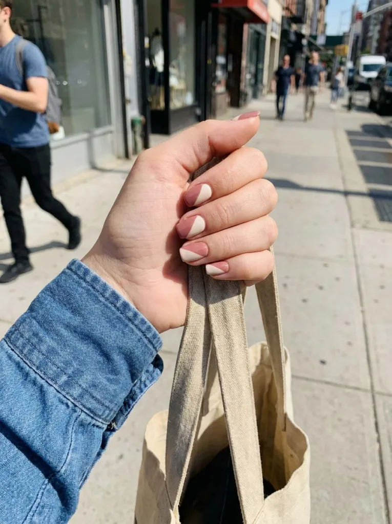 Short square color block summer nails gripping a tote bag strap outdoors