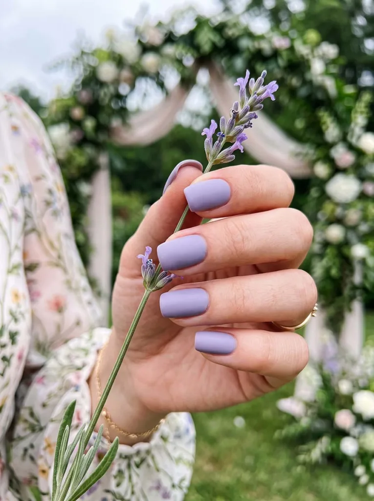 close-up of soft lavender wedding nails in front of a garden ceremony arch
