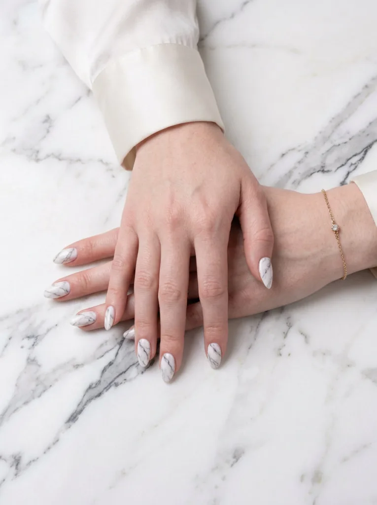 marble effect nail art white with grey veins on fair skin nails overhead on real calacatta marble surface