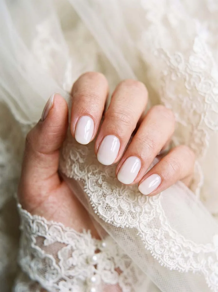 close-up of milky white wedding nails resting near a bridal veil