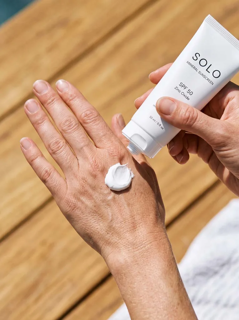 fair-skinned hand dispensing zinc oxide mineral sunscreen from white tube onto back of hand
